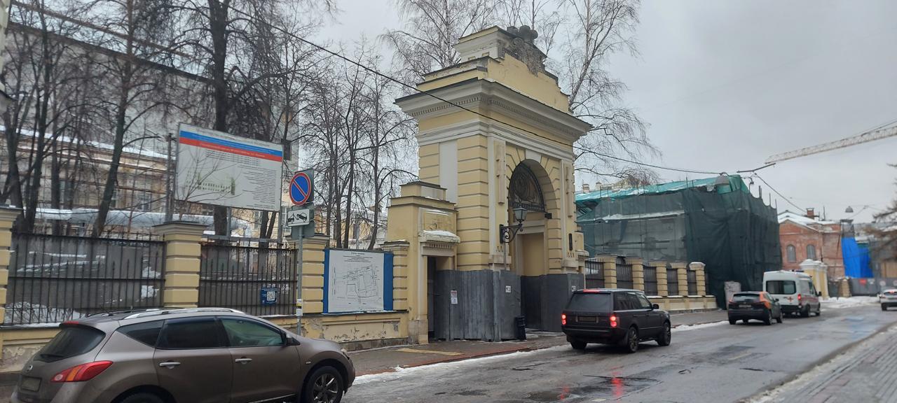Строительные леса вдоль исторического кирпичного флигеля